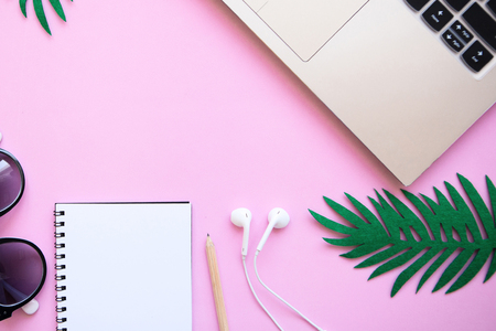 Workspace in a pink trendy color or summer design with a concept to start a vacation. Laptop and various things nearby. In the middle there is a place for text.の写真素材