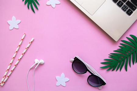 Workspace in a pink trendy color or summer design with a concept to start a vacation. Laptop and sunglasses next to tropical leaves. Nearby there is a place for text.の写真素材