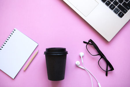 Workspace in a trendy pink color. Many different things including a laptop and headphones are on the table.の写真素材