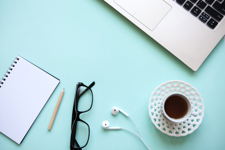 Workspace in a trendy blue color. Many different things including a laptop, notebook and headphones are on the table.の写真素材