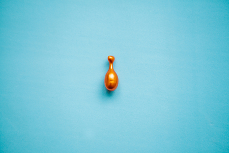 Pill or capsule with q10 or coenzyme on blue background. Caring for skin health.の写真素材
