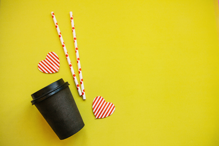 Mug with coffee, tubules and decorative hearts on a yellow background. Near place for text.の写真素材