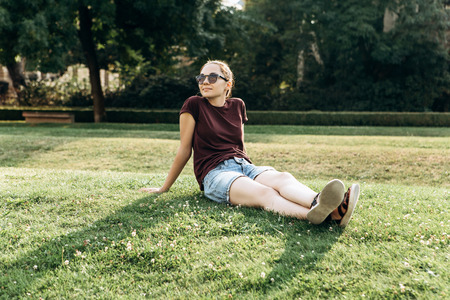 Beautiful young girl resting on the grass in a city park.の写真素材