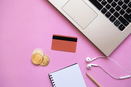 Conceptual photo of e-commerce with credit cards and cryptocurrency. Computer, cryptocurrency and credit card on a trendy pink background.の写真素材