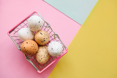 Basket with eggs on a colorful background. The concept of a festive Easter sale in a minimal style.の写真素材
