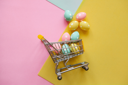 Shopping Cart with eggs on a multi-colored background. The concept of a festive Easter sale in a minimal style.の写真素材