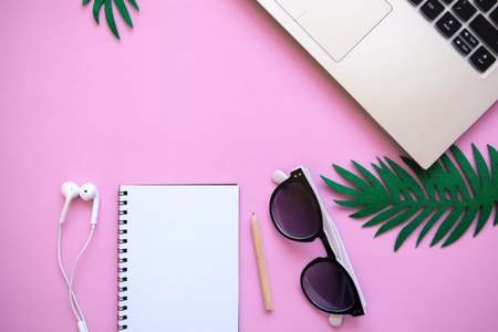 Workspace in a pink trendy color or summer design with a concept to start a vacation. Laptop and various things nearby.の写真素材