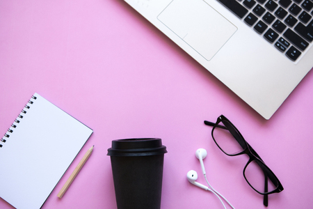 Workspace in a trendy pink color. Many different things including a laptop and headphones are on the table.の写真素材