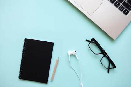 Workspace in a trendy blue color. Many different things including a laptop and headphones are on the table.の写真素材