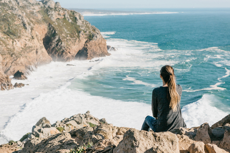 The girl at the top of the cliff in solitude admires the beautiful view of the Atlantic Ocean.の写真素材