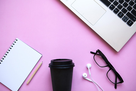 Workspace in a trendy pink color. Many different things including a laptop and headphones are on the table.の写真素材