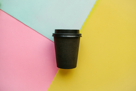 Disposable glass with coffee or tea on a multi-colored background. Fast food or takeaway drink.の写真素材