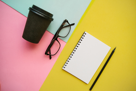 Notebook, glasses and other items on a colorful background.の写真素材