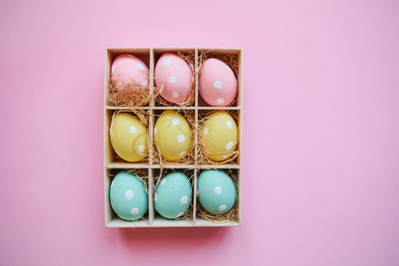 Gift or holiday box or container with colorful Easter eggs on a pink background. Easter celebration concept in minimal style.の写真素材