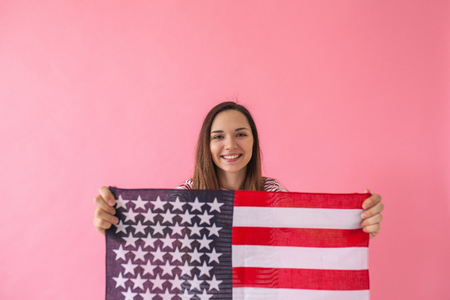 The girl holds in her hand an American flag. A concept of learning American language or immigration or work and travel or the celebration of July 4thの写真素材