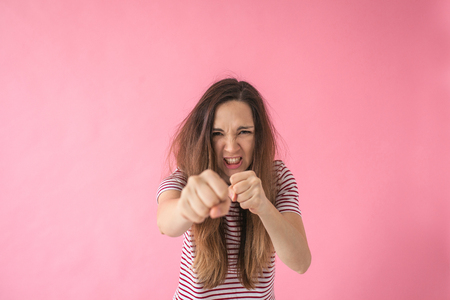 An angry or frustrated girl punches and shows aggression. Or she is training or boxing.の写真素材