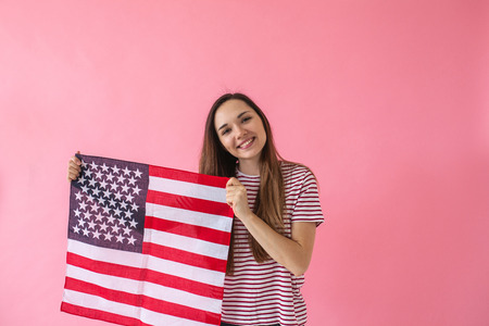 The girl holds in her hand an American flag. A concept of learning American language or immigration or work and travel or the celebration of July 4thの写真素材