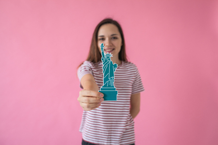 The girl holds in her hand a statue of liberty - the concept of learning American language or immigration or work and travel.の写真素材
