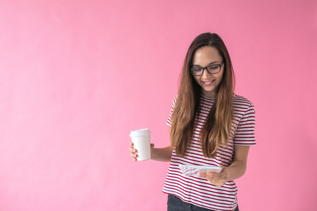 A beautiful girl uses a tablet and drinks coffee or another drink. Communication or job search online or internet entertainment during coffee break.の写真素材