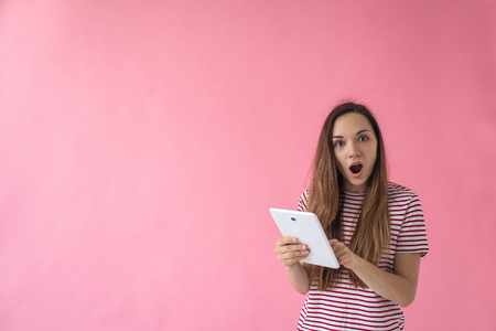 Pleasantly surprised girl uses the tablet. Sale or good news or a good job search or other.の写真素材