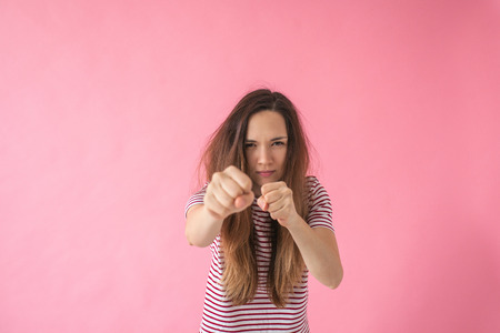 An angry or frustrated girl punches and shows aggression. Or she is training or boxing.の写真素材