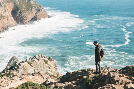 A man tourist with a backpack stands in solitude at Cape Roca in Portugal.の写真素材