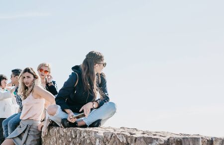 Portugal, Sintra, June 26, 2018: A group of young stylish girls relaxing at Cape Roca on a sunny summer day.のeditorial素材