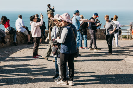 Portugal, Sintra, June 26, 2018: Asian women tourists posing for photos at Cape Roca. In the...