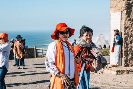 Portugal, Sintra, June 26, 2018: Stylish Asian older women tourists visiting the sights of Cape Roca. They are positive and smiling.のeditorial素材