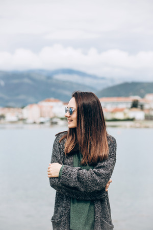 Young stylish smiling girl in sunglasses on the background of the sea.の写真素材