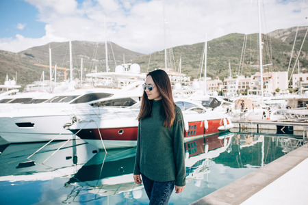 Young beautiful stylish girl walks along the promenade with yachts in Porto Montenegro in Tivat in Montenegro.の写真素材