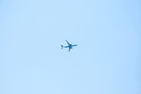 An airplane or a plane flies against a blue sky in a minimalist style.