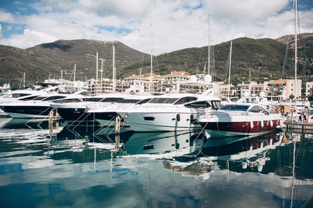 Many yachts moored at the coast in Porto Montenegro in Tivat in Montenegro against the backdrop of a beautiful mountain landscape. Summer sea vacationの写真素材