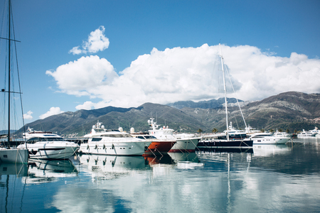 Many yachts moored at the coast in Porto Montenegro in Tivat in Montenegro against the backdrop of a beautiful mountain landscape. Summer sea vacationの写真素材
