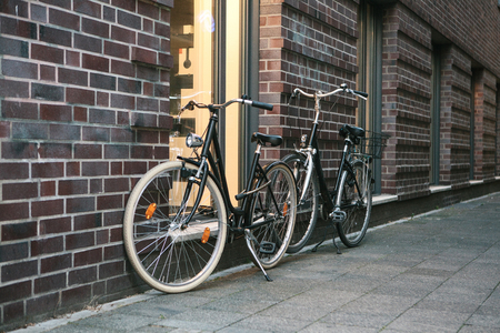 Bicycles are parked next to a brick wall of a building on a city street.の写真素材