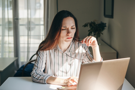 Girl working using laptop in home office. She is reading or learning. Writes a blog or something else. Freelancer at work. The student does the task.の写真素材