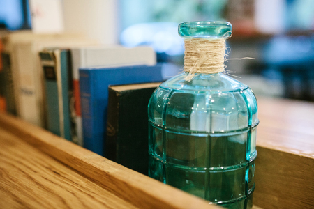 A glass jar or a decorated bottle on a shelf with books. Selective focus.の写真素材