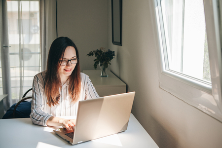 Girl working using laptop in home office. She is reading or learning. Writes a blog or something else. Freelancer at work. The student does the task.の写真素材