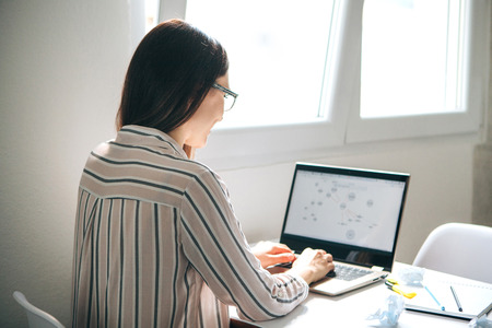A young girl works in a home office or a student does homework or exercises. Or a girl online in the Internet.の写真素材