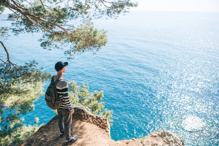 Tourist with a backpack near the sea. Travel alone. Looks into the distance.の写真素材