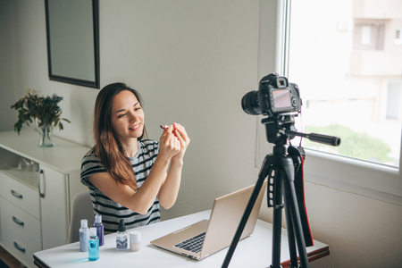 Girl videoblogger or beauty blogger records video for subscribers. She shows lipstick and tells how to use it properly.の写真素材
