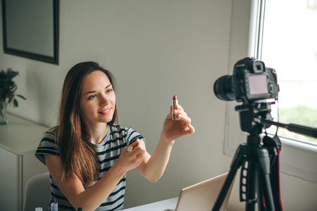 Girl videoblogger or beauty blogger records video for subscribers. She shows lipstick and tells how to use it properly.の写真素材