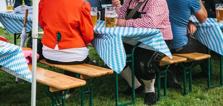 People in traditional suits drink beer outdoors in Germany during the Oktoberfest celebration.の写真素材
