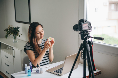 Girl videoblogger or beauty blogger records video for subscribers how to use the cream and talks about it.の写真素材