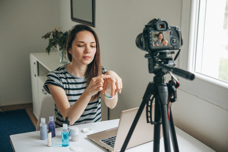 Girl videoblogger or beauty blogger records video for subscribers how to use the cream and talks about it.の写真素材