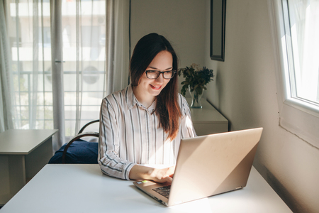 Girl working using laptop in home office. She is reading or learning. Writes a blog or something else. Freelancer at work. The student does the task.の写真素材