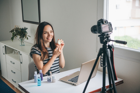 Girl videoblogger or beauty blogger records video for subscribers how to use the cream and talks about it.の写真素材