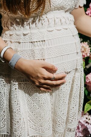 Closeup of pregnant woman holding hand over belly. Waiting for the birth of a child. Maternal care.