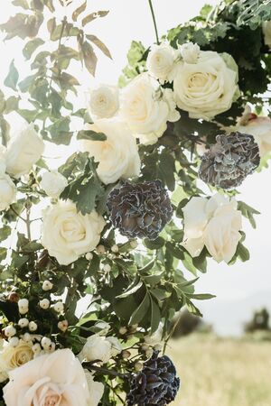 Closeup of flowers, including white roses on a beautiful wedding arch. Preparation for a wedding event.