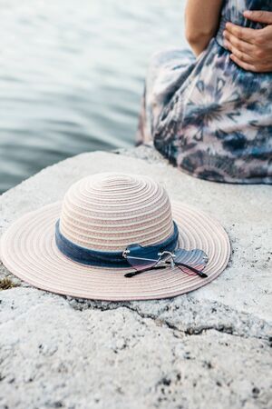 Womens hat and sunglasses in the foreground. In the background, a blurred couple is embracing.の写真素材